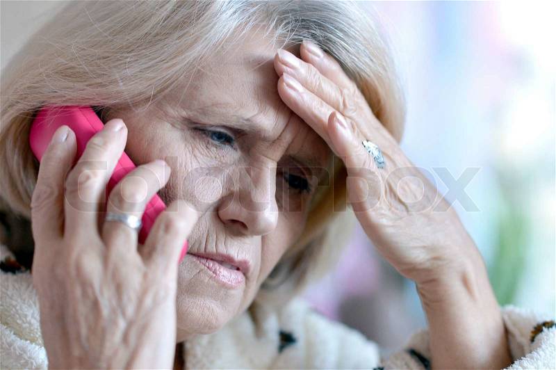 Close-up portrait of an elderly woman calling to the doctor, stock photo