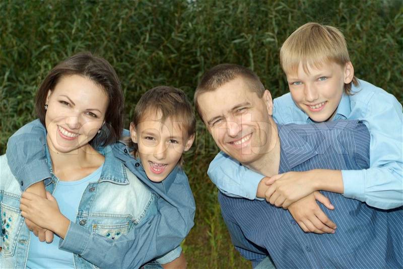 Happy family of four walking in park in summer, stock photo