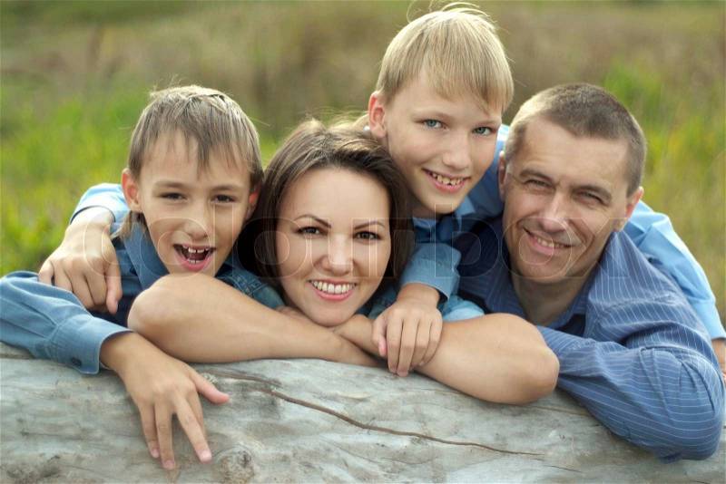 Cheerful family of four walking in park in summer, stock photo