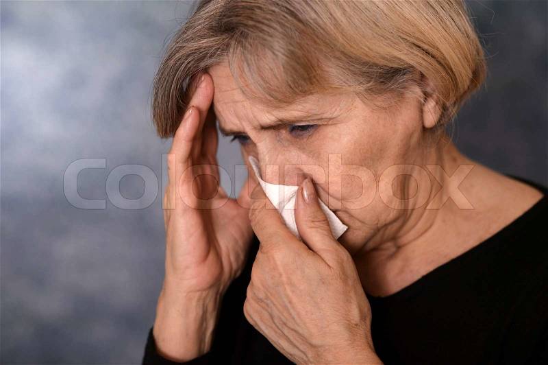 Depressed old woman on a gray background, stock photo