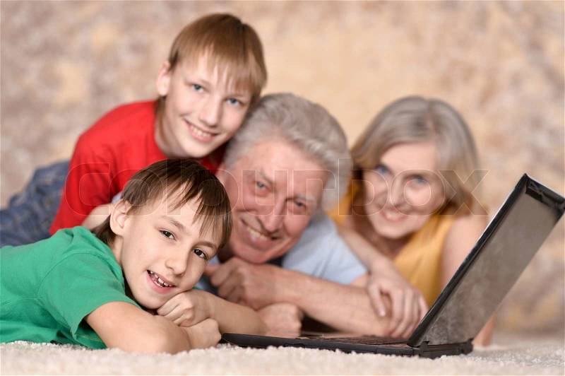 Elderly couple and their grandchildren resting at a laptop, stock photo