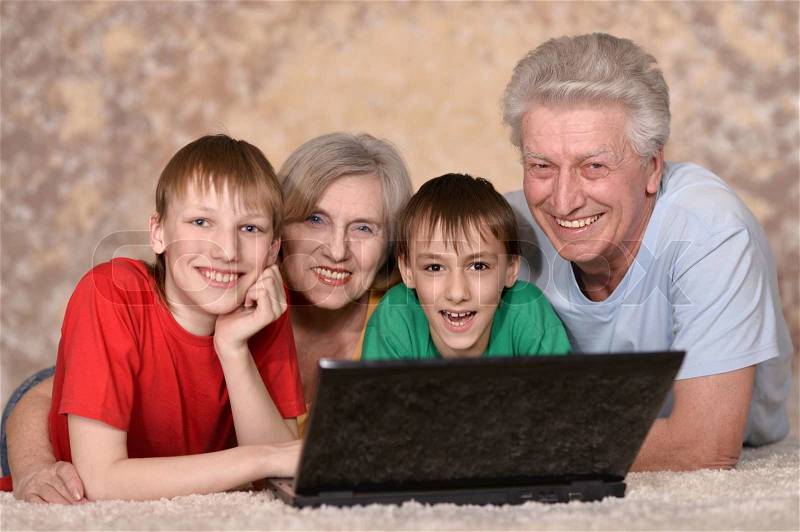 Mature couple and their grandchildren resting at a laptop, stock photo