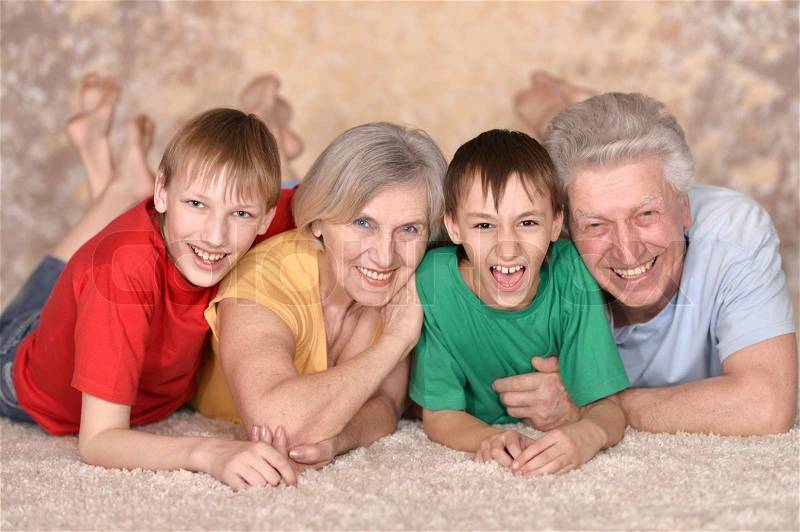 Happy elderly couple and their grandchildren are lying on the floor, stock photo