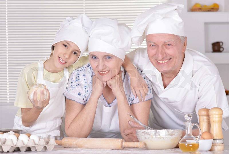 An elderly couple and their grandson knead the dough for the pie together, stock photo