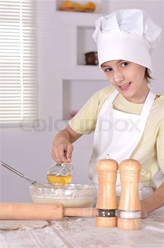Young boy in a chef\'s hat knead dough for cookies, stock photo