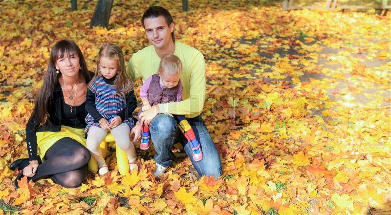 Young charming family of four enjoying the weather in yellow autumn park, stock photo