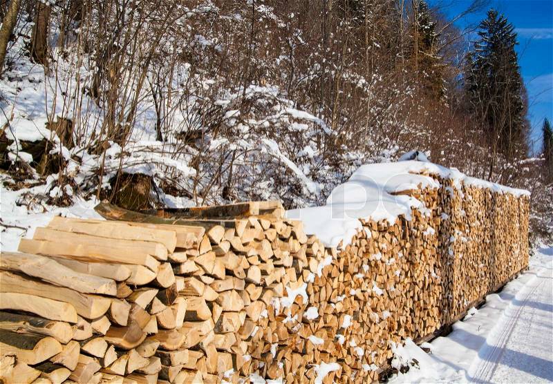 Firewood stacked in winter. Wood pile with snow stacked for firewood, stock photo