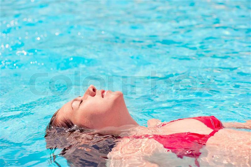 Girl lying on the water with eyes closed in the pool, stock photo