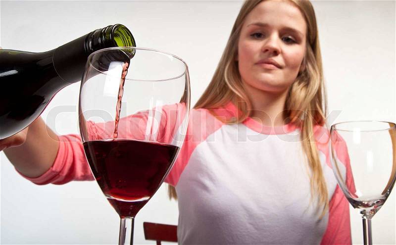 Scandinavian cute young girl pouring her glass with red wine, stock photo