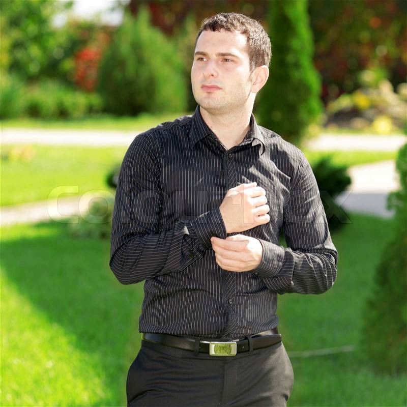 Portrait of young attractive business man standing in the yard in front of his house. Sunny day. , stock photo