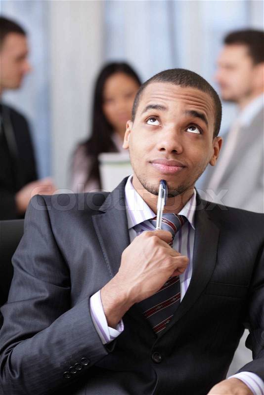 Pensive african-american businessman with his team working behind, stock photo