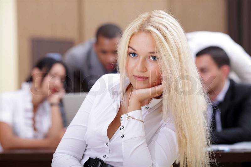 Portrait of young happy caucasian woman with her business partners on the background, stock photo