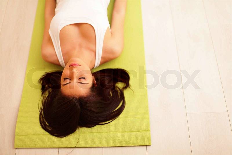 Young woman in sport cloths lying on the yoga mat, stock photo