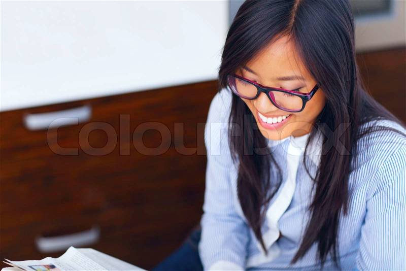 Young happy asian businesswoman reading newspaper, stock photo