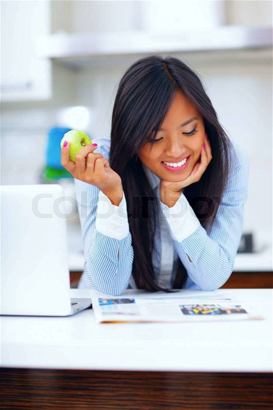 Young happy asian woman reading newspaper and eating apple, stock photo
