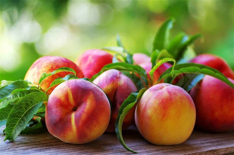 Ripe peaches and leaves on table, stock photo