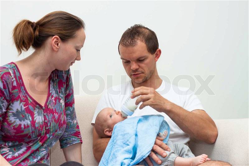 Portrait of woman and man feeding baby boy, stock photo