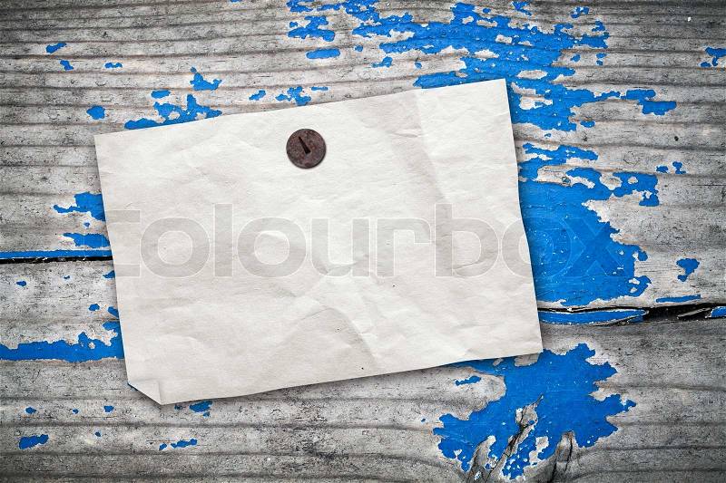 Empty yellow paper ad hanging on vintage wooden wall with blue paint, stock photo