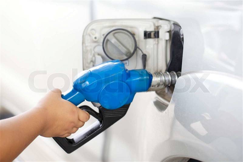 Close up shot of a hand pumping gasoline fuel in car at gas station with shallow depth of field, stock photo