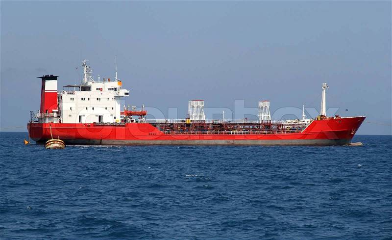 Red tanker designed for transporting crude oil is at anchor near the port, stock photo