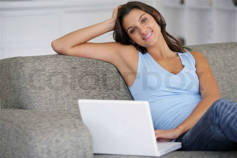 Woman sitting on a sofa and surfing the internet, stock photo