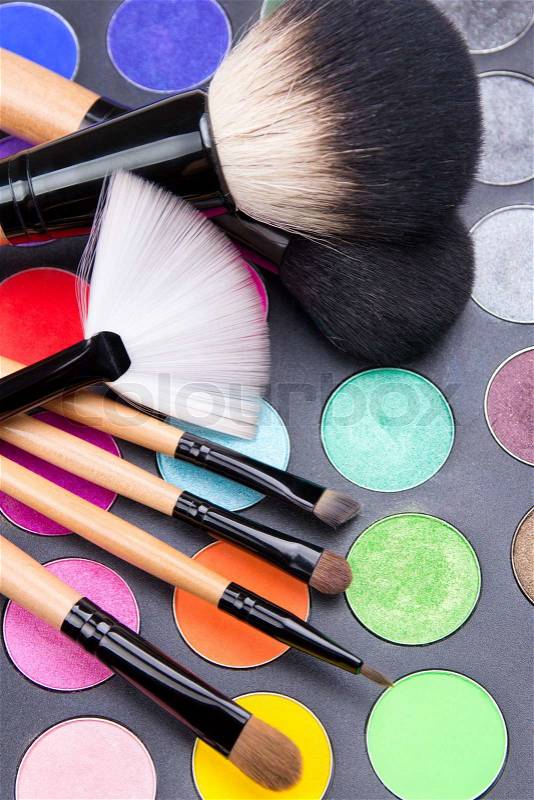 Close up of make-up brushes and colorful eyeshadow palette over black, stock photo