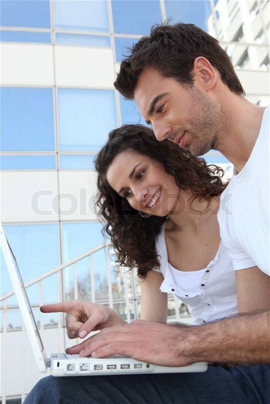 Couple with glass building in front of computer, stock photo