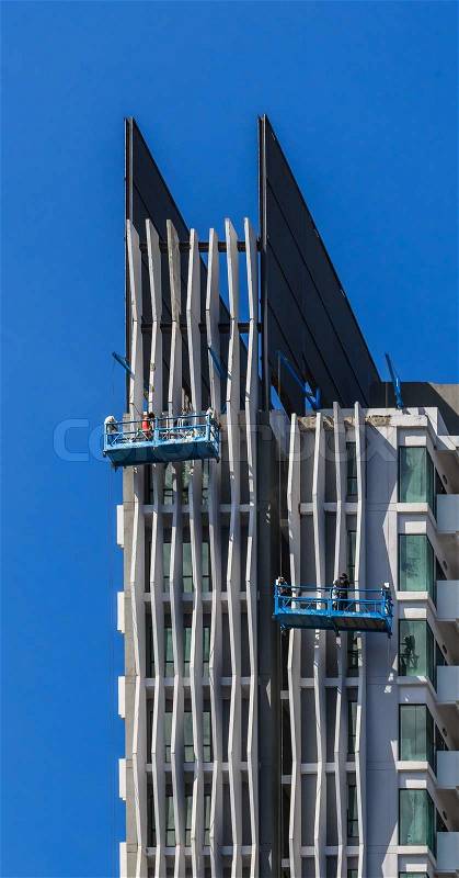 Worker Team Working on Facade of High Building, Blue sky Background, stock photo