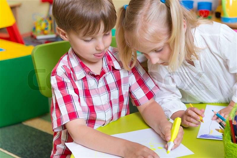 Two cute little prescool kids drawing with crayons at the table, stock photo
