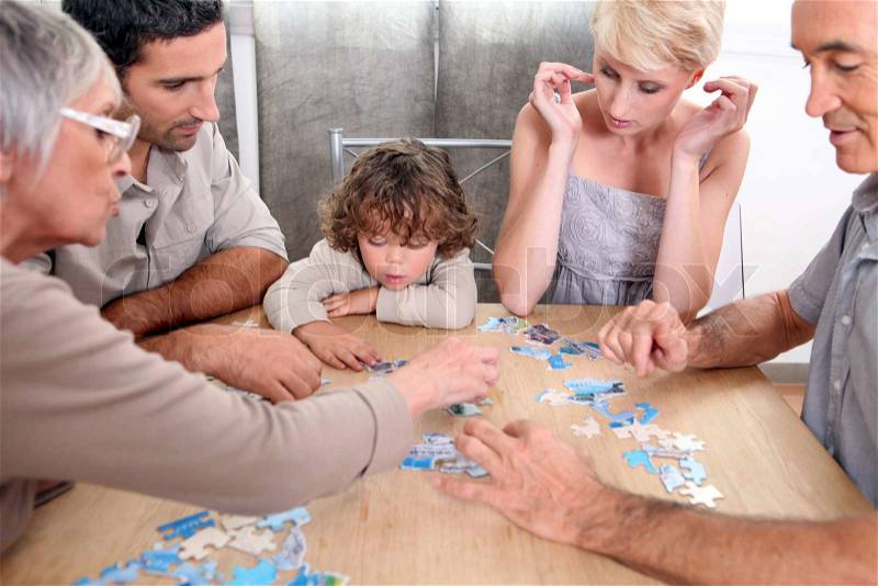 Family completing jig-saw puzzle, stock photo
