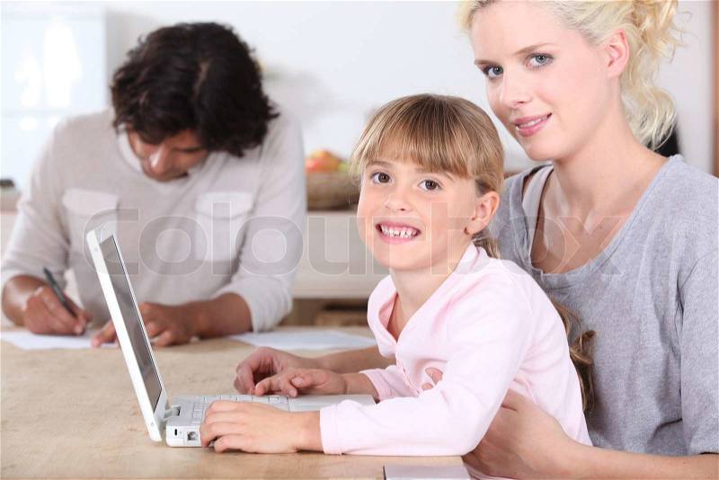 Girl using a laptop with her parents, stock photo