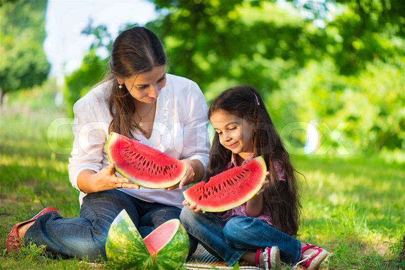 Happy indian family eating watermelon in park, stock photo