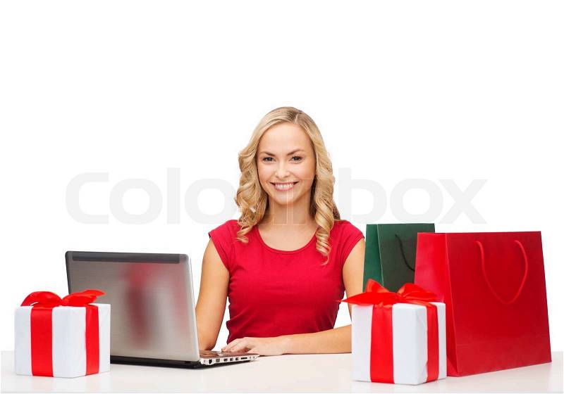 Christmas, x-mas, online shopping concept - woman with gift boxes, bags and laptop computer, stock photo