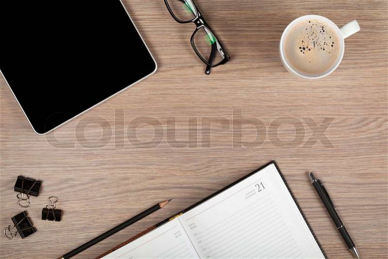 Tablet, notepad, glasses and coffee cup on office wooden table, stock photo