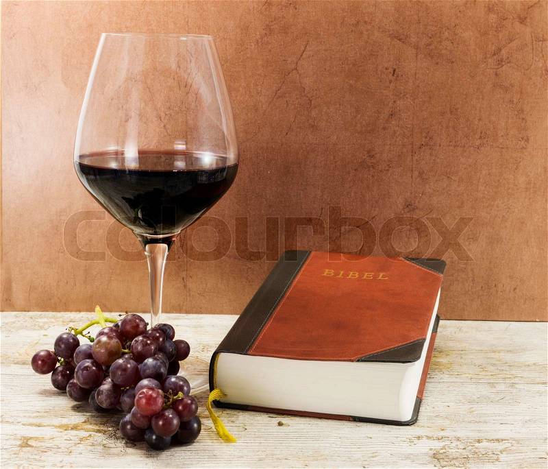 Old bible and red wine with grapes on table, stock photo
