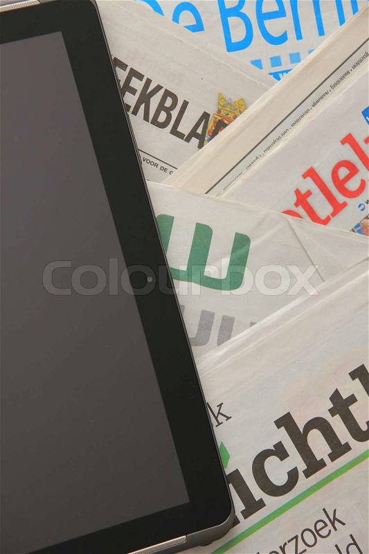 Tablet and stack of newspapers, stock photo