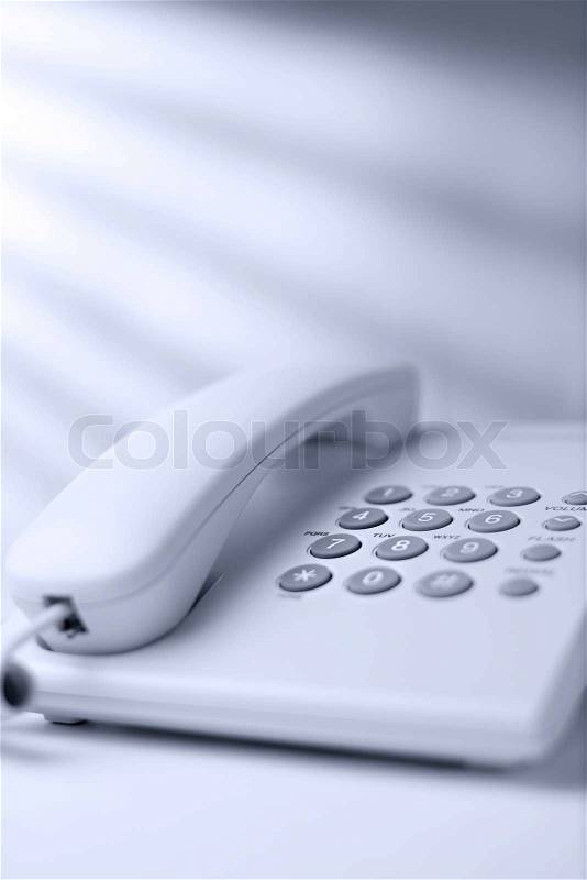 Low angle view of a white office dial up landline or terrestrial telephone with handset and keypad for telephonic communication, stock photo
