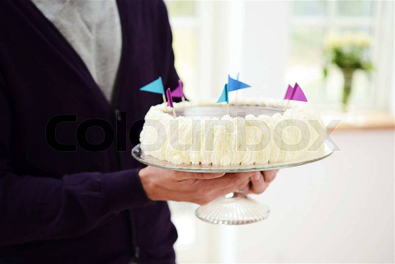 Man carrying birthday cake with colourful flags, stock photo