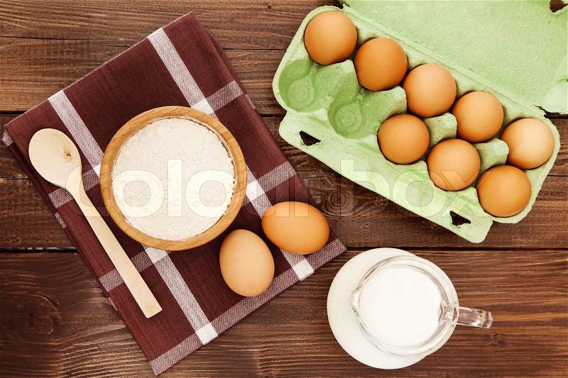Eggs, milk and flour on a wooden table, stock photo