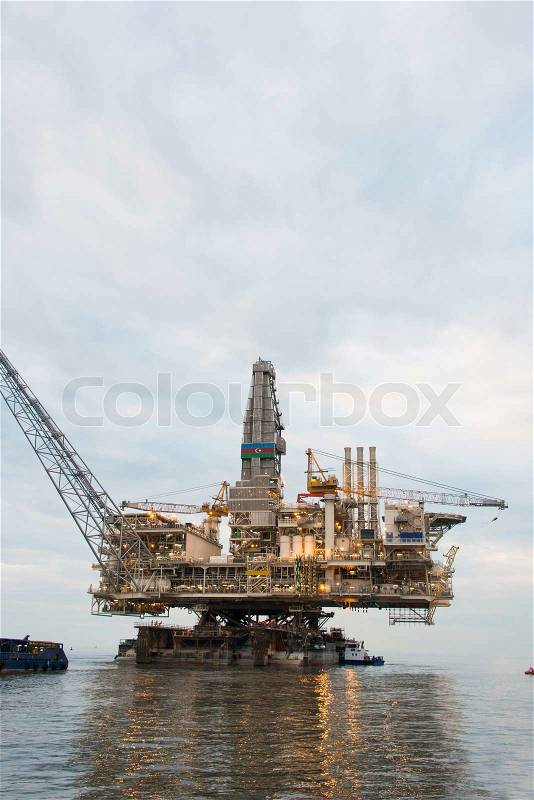 Oil rig being tugged in the sea, stock photo