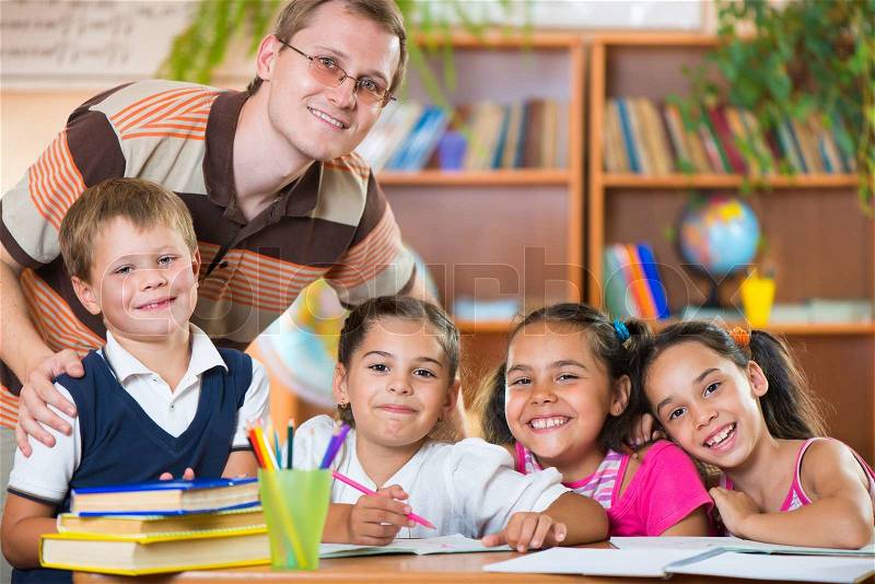 Group of elementary pupils in classroom with teacher , stock photo