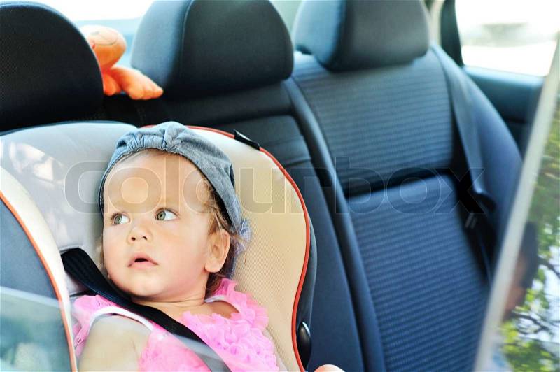 Baby girl sitting in car, stock photo