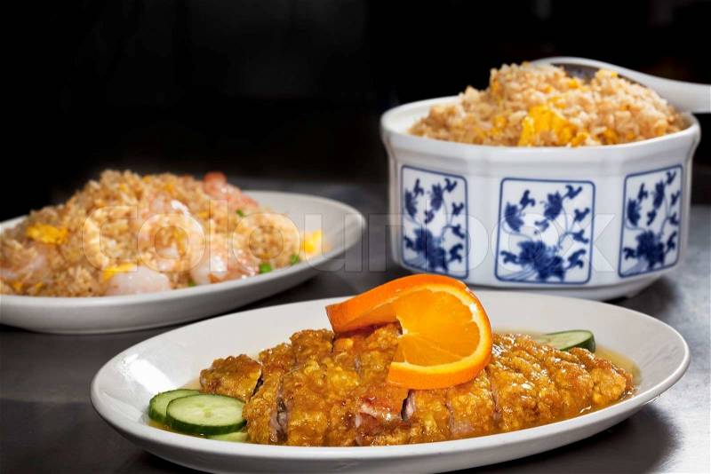 Close-up of Chinese dinner set with orange duck, seafood rice and egg fried rice on dark background, stock photo