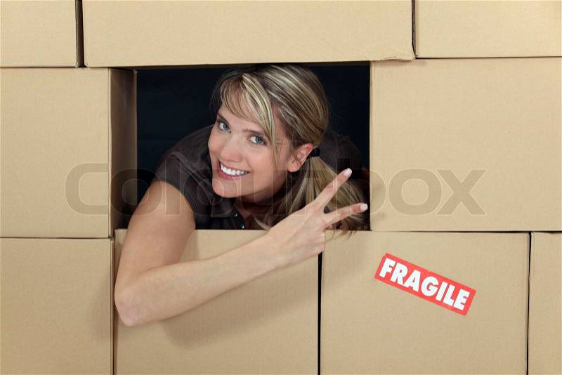 Woman in a wall of cardboard boxes, stock photo
