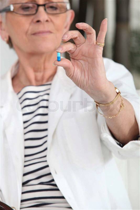 Old woman taking medication, stock photo