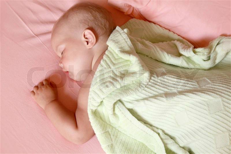 Little baby sleeps in the bed under soft green blanket, stock photo