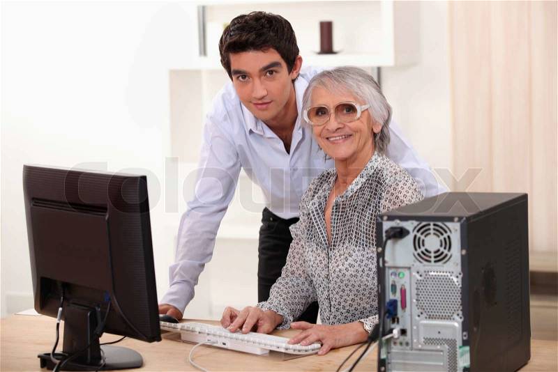 Young man and older woman using a computer, stock photo