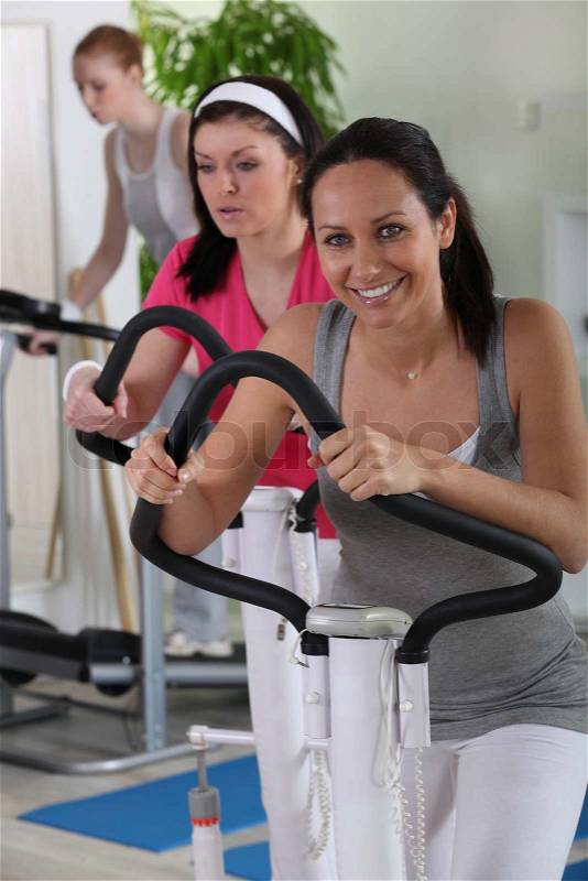 Female using an exercise machine in the gym, stock photo