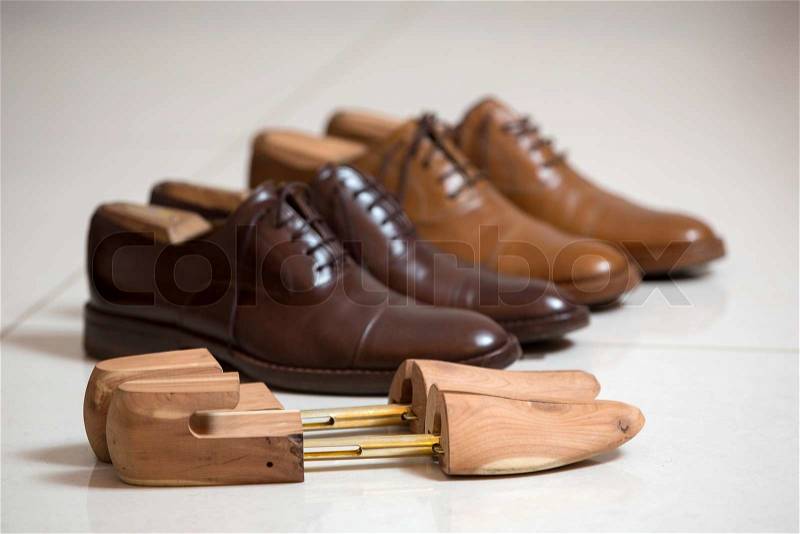 Two pairs of brown handmade classic men\'s shoes with a shoe pads and stretchers inside and beside the shoes, stock photo