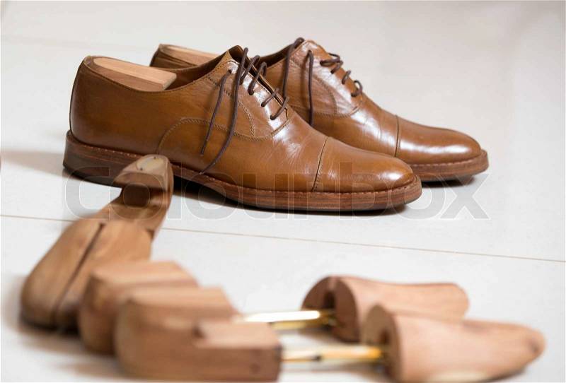 Pair of brown handmade classic men\'s shoes with a shoe pads and stretchers inside and beside the shoes, stock photo